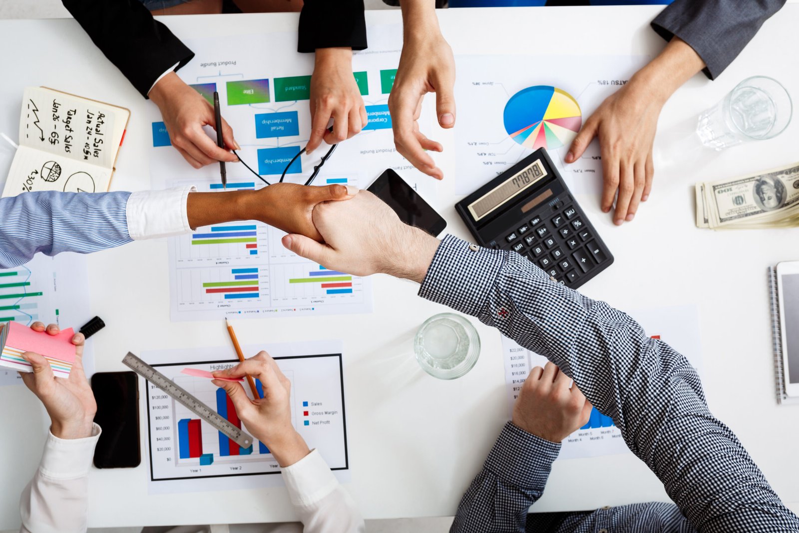 picture of businessmen's hands on white table with documents and drafts